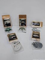 Five Hallmark Magic Light Up Ornaments from Star Trek and Star Wars, displayed out of box with original packaging visible. Ornaments include USS Enterprise, Klingon Bird of Prey, Romulan Warbird, Voyager, and Millennium Falcon.