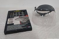 Photo showing unopened Craftsman socket organizer box and used clear safety visor face shield with black adjustable headband on white surface.