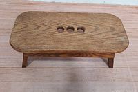 Top down view of vintage wooden stool showing three circular holes and wood grain pattern.