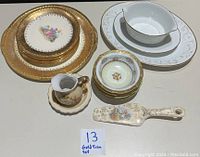 Full view of all china pieces including plates, bowls, creamer, gravy boat, serving utensils, arranged together showing the details and condition of the set