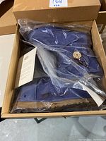 Top view of unopened lavender UGG boots still in the box and plastic wrapping, showing button and suede texture.