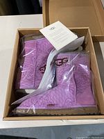 Pair of pink UGG boots with floral kimono pattern in original box unopened in plastic packing.