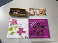 Overview photo showing box of coins, Chinese coin set packaging, and Ghana 50 Cedis note