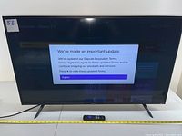 Front view of Hisense 43-inch Roku TV powered on showing Roku system update message on screen with remote positioned in front.