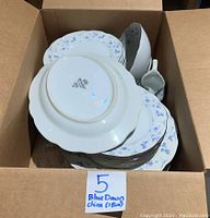 Boxed set of Premiere ME 113 Blue Dawn china showing stacked pieces with blue floral patterns along edges and bottom stamp mark.