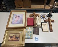 Overview of all religious items on table including framed prints, crucifixes, statue and books for sale