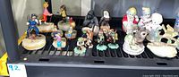 Full view of 15 figurines including Ron Lee clowns, bisque clowns, resin frogs, and animals arranged on shelf