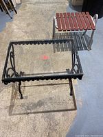 Metal frame table with decorative edges and glass top, viewed from above, showing condition and minor damage.