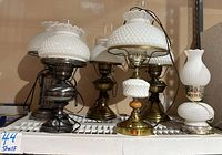 Wide view of five vintage milk glass lamps with hobnail shades and metal bases, including brass and silver tones