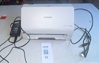 Front view of the Canon ImageFormula R30 scanner showing the document feed slot and connected power and USB cables.