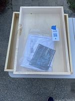 Two light pine wood kitchen drawers stacked, one still in original packaging with documentation.