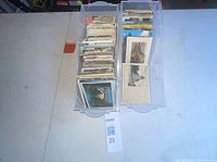 Two clear plastic bins filled with numerous postcards standing upright on a table.