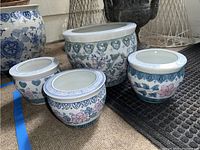 Four ceramic planters arranged to show designs, patterns, sizes, and colors