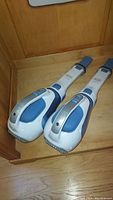 Two Black & Decker handheld portable vacuums placed side by side on a wooden floor.