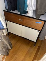 Front-left angle view showing cabinet under hanging clothes in closet