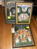 Three framed Indian paintings showing various traditional scenes, including figures in traditional dress, garden and architectural elements.
