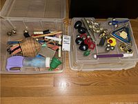 Full overview of two plastic containers filled with various small percussion instruments including egg shakers, bells, drum sticks, triangle, clappers, and other rhythm instruments.