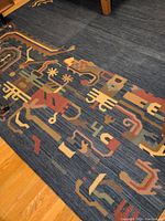 Close-up image showing detailed geometric and abstract patterns on dark blue background of the woven rug.