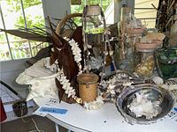 Image showing seashell necklaces on wood figurine, jar labeled SEA GLASS, and assorted seashells on table