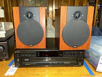 Sony CD player with two Boston speakers displayed on a wooden surface, showing front views and control panel of the CD player.