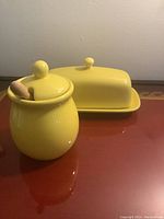 Yellow ceramic honey pot with lid and wooden honey dipper, and yellow ceramic butter dish with lid