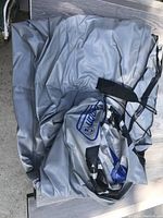 Folded gray Coleman inflatable boat made of vinyl material with black straps and visible blue Coleman logo.