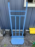 Full view of blue metal hand cart showing front structure and two pneumatic tires.