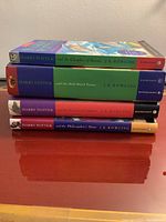 Stack of four Harry Potter books, showing spines with titles and author J.K. Rowling. Mix of paperback and hardcover editions.