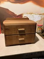 Front view of the pine wood jewelry box showing two drawers with wooden handles and curved top back edge.