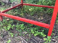 Close-up of the red metal frame and legs set in outdoor ground