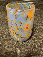 Side view of vase showing swirling blue, orange, white and red marbled pattern.