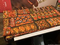 Folded vintage tablecloth showing detailed geometric pattern in warm colors.