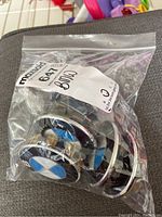Clear view of multiple BMW centre caps inside a plastic bag showing their shape and logo design.