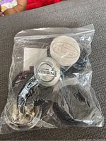 Plastic bag containing Nissan, Volkswagen, and Dodge centre caps showing visible wear.