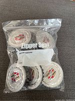 Six Cadillac center caps sealed in a plastic bag, showing the Cadillac emblems visible through the bag.