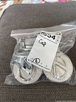 Six Lexus center caps in a small clear plastic bag, front view showing silver color and Lexus logo.