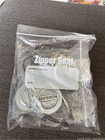 Clear plastic bag containing four metallic Nissan center caps with the 'Nissan' logo visible.