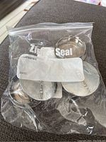 Four Dodge center caps in sealed zip-lock bag from above view, shows condition and packaging