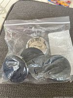 Plastic bag containing four black Ram center caps with visible Ram logos on top.