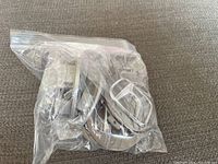 Six Honda center caps packed inside a clear resealable plastic bag laid on a textured surface.