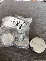 Six Dodge centre caps with five in plastic bag and one out of bag showing the logo.