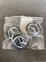 Four Mazda wheel centre caps in original clear plastic packaging, showing the Mazda logo on each.