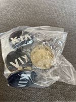 Four Kia center caps in a plastic bag showing variety including one gold-colored piece