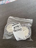 Two Mercedes-Benz center caps visible inside a clear resealable plastic bag, front side showing silver star emblem and 'MERCEDES' text