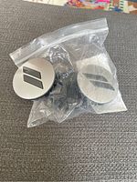 Three Dodge center caps, with two caps in a plastic bag and one outside bag showing front surface.