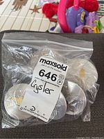 A sealed plastic bag containing five vehicle centre caps, labeled 'Chrysler'. The caps appear metallic, showing some wear.