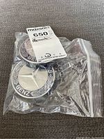 Two Mercedes centre caps in a zip lock bag showing logo and color details.