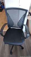 Front view of black office chair showing fabric seat with minor wear and mesh backrest with supportive design.
