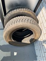Two stacked winter claw tires showing tread pattern and overall condition.