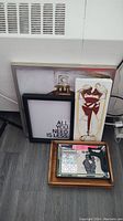 Lot overview with stacked framed art prints and trays on floor against wall